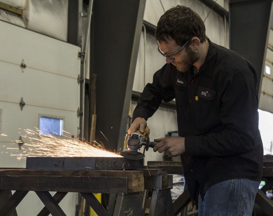 Steel 21 is always looking for talented people to fill precision grinding jobs. A Steel 21 technician works on a 2-inch thick steel plate.